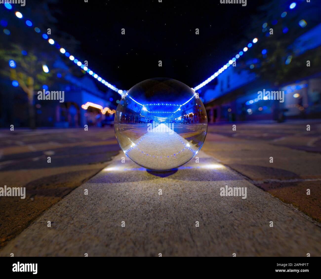 Una piccola strada principale della città durante la stagione di festa si riflette in un lensball. Foto Stock