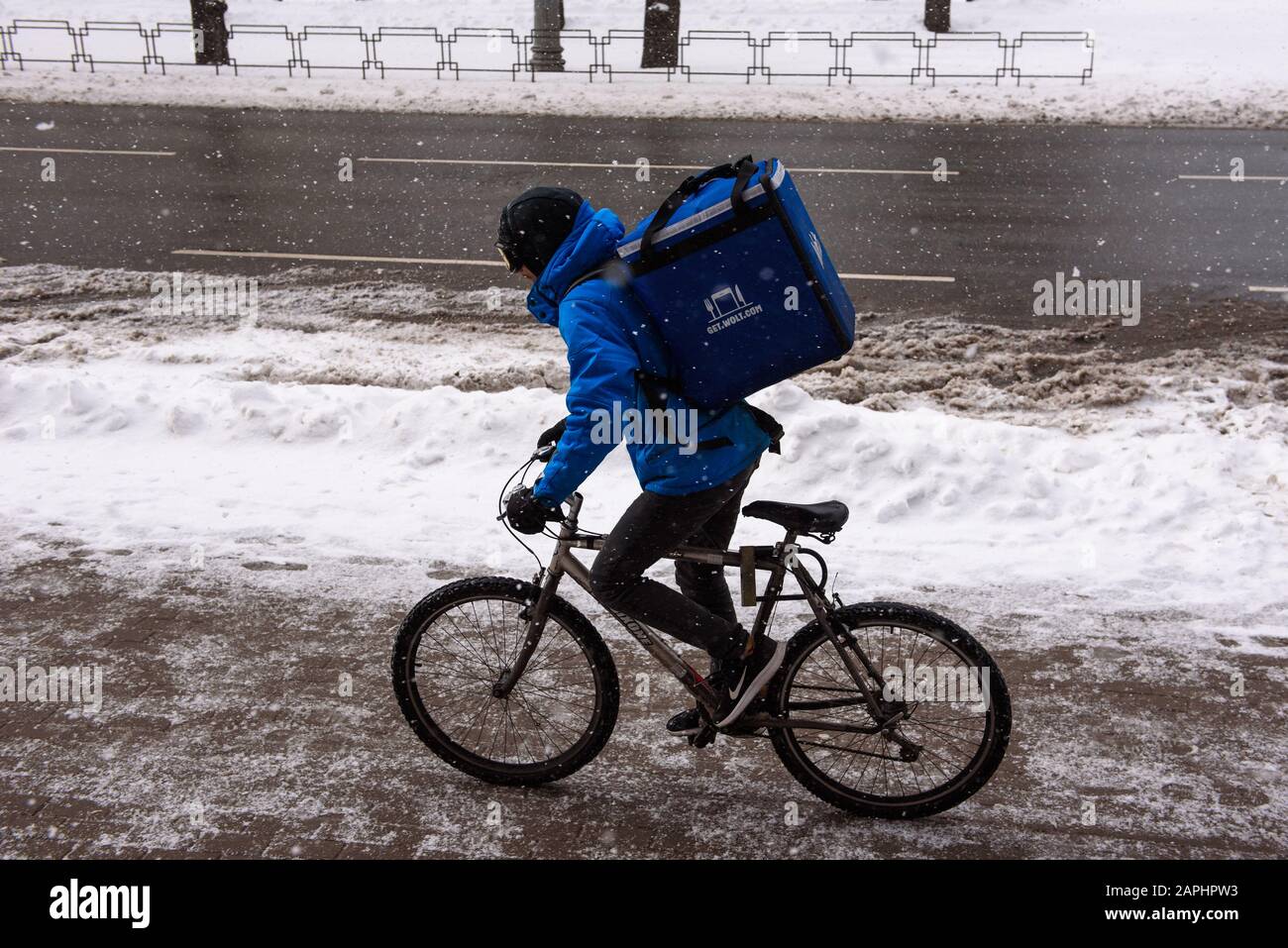 RIGA, LETTONIA. 12th marzo 2019. Courier di Wolt Company con passeggiate in bicicletta, durante la nevicata nella città di riga. Foto Stock