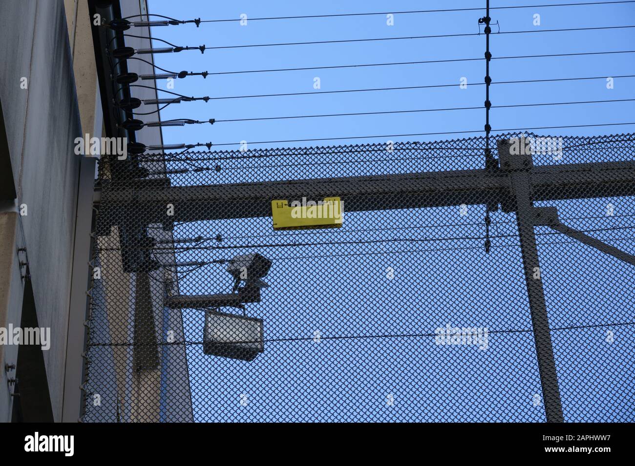 Una telecamera di sorveglianza e riflettori dietro le recinzioni di una prigione. Foto Stock