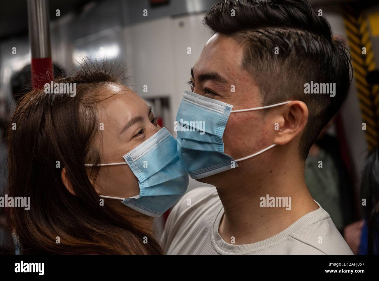 Una coppia si accarezza mentre indossano maschere sanitarie sulla metropolitana Hong Kong´s MTR dopo che i primi casi di coronavirus sono stati confermati a Hong Kong.China ha implementato un trasporto pubblico e blocco aeroporto in diverse città per rallentare la diffusione del Wuhan coronavirus. Foto Stock