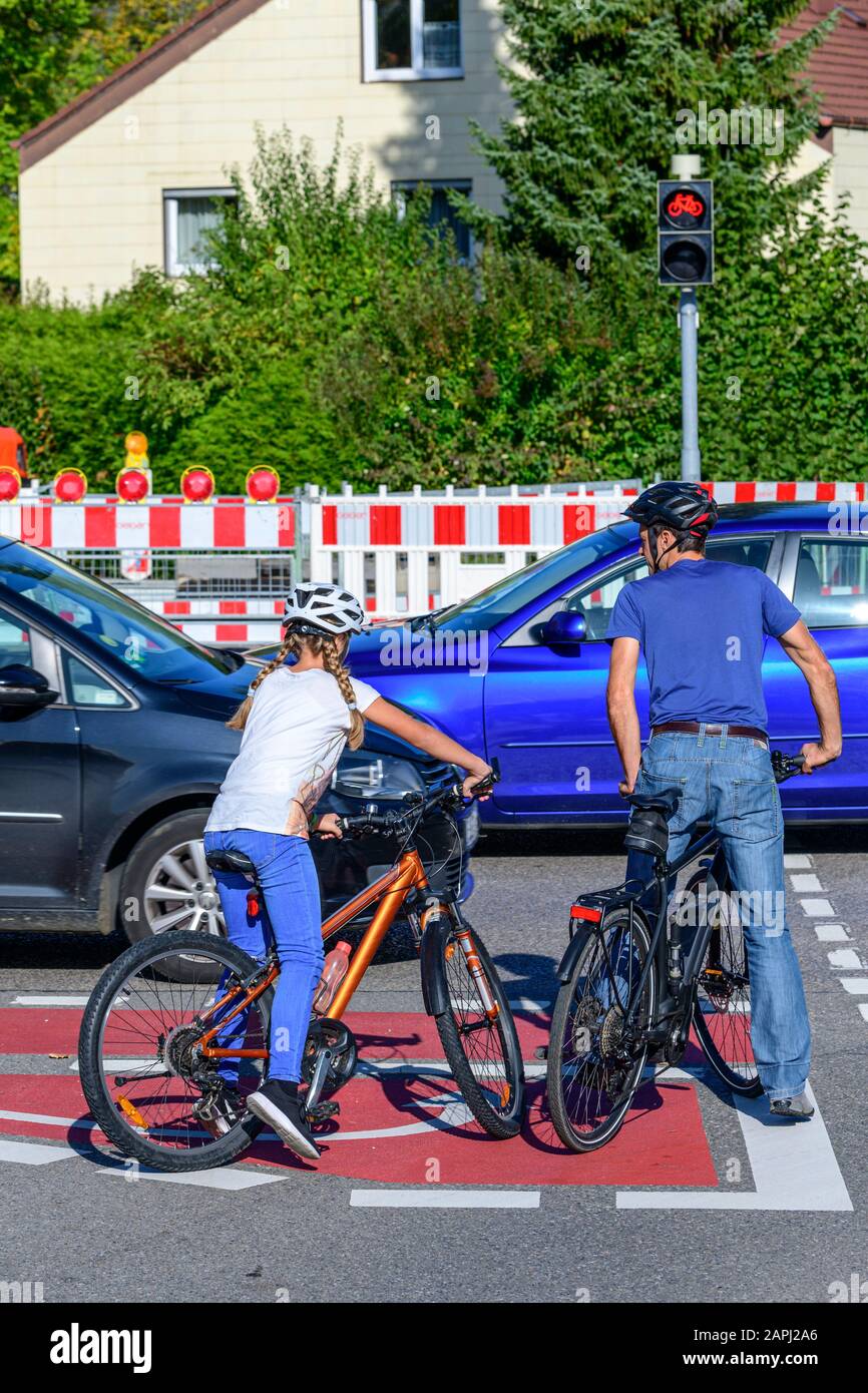 Due ciclisti in attesa su una pista ciclabile segnata perfetta a un bivio Foto Stock