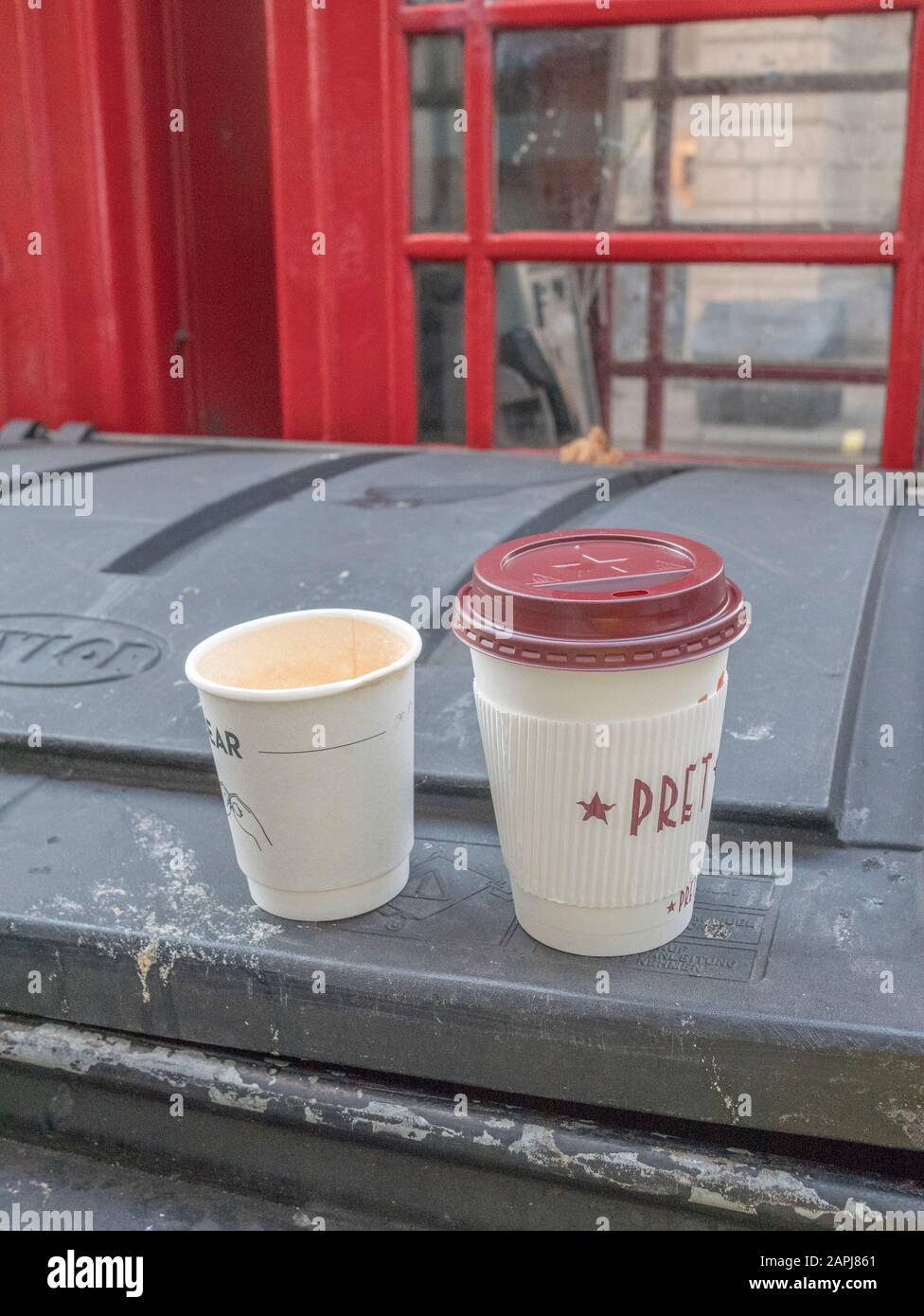 Pret una tazza di caffè da asporto in plastica Manger più un altro marchio sconosciuto scartato in cima al cassonetto vicino a Oxford Street di Londra. Imballaggio in plastica. Foto Stock