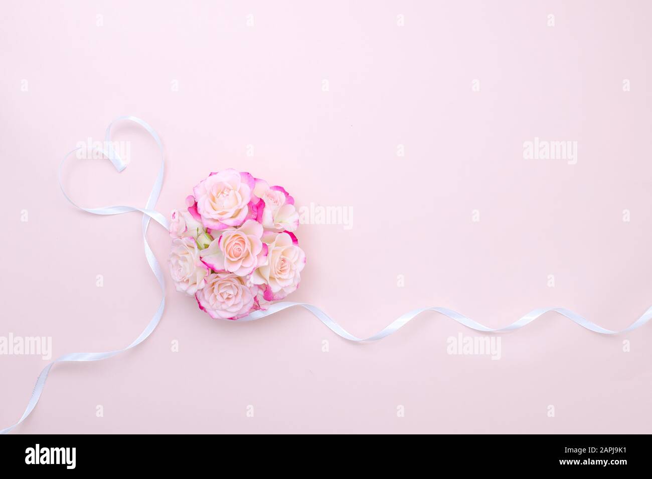 Struttura di rose rosa e cuore di nastro. Concetto di molla, disposizione piatta, spazio di copia. Composizione fiori di rosa per San Valentino, matrimonio, giorno delle donne, compleanno Foto Stock