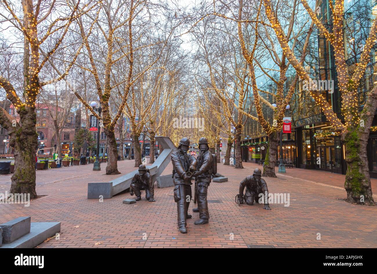 Sculture in bronzo di Hai Ying Wu per il Memoriale Dei vigili del fuoco Caduti presso Occidental Park, Pioneer Square, Seattle, Washington, durante la stagione delle festività. Foto Stock
