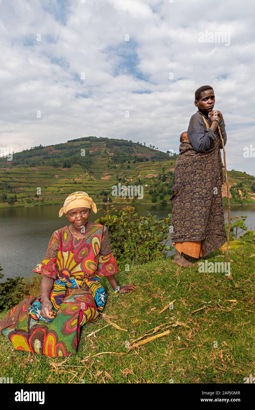 Donne pigmiche appartenenti alla tribù Batwa con una delle quali con un bambino sulla schiena, sul lago Bunyonyi, Uganda Foto Stock