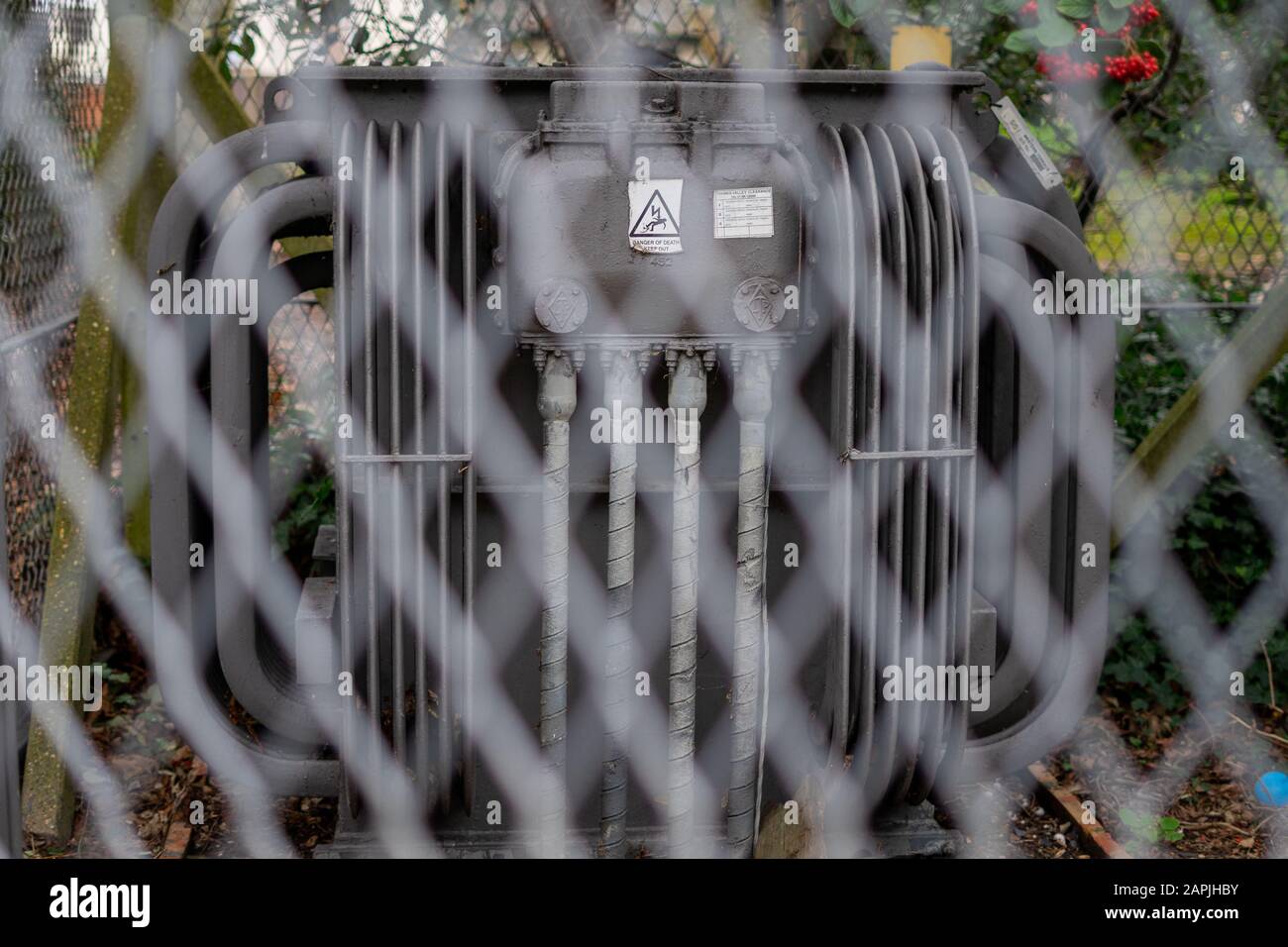 Una sottostazione elettrica con un segno di pericolo il fuoco è attraverso la recinzione che lo circonda Foto Stock