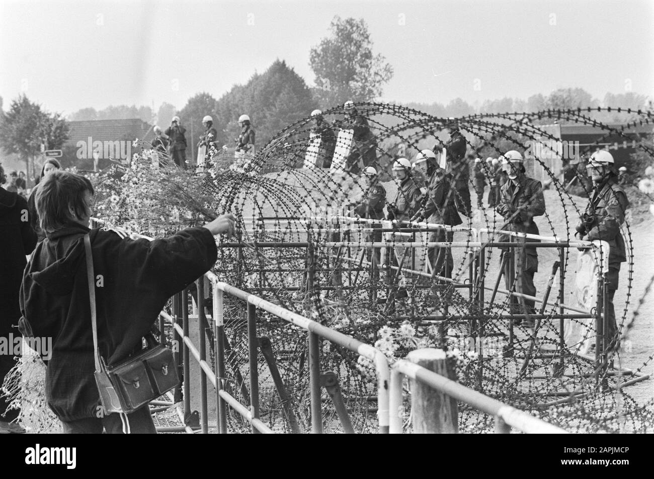 Dimostrazione contro la centrale nucleare di Kalkar; il dimostraant depone i fiori nel filo spinato Data: 24 settembre 1977 luogo: Kalkar Parole Chiave: Fiori, UCCELLI, dimostrazioni, centrali nucleari Foto Stock