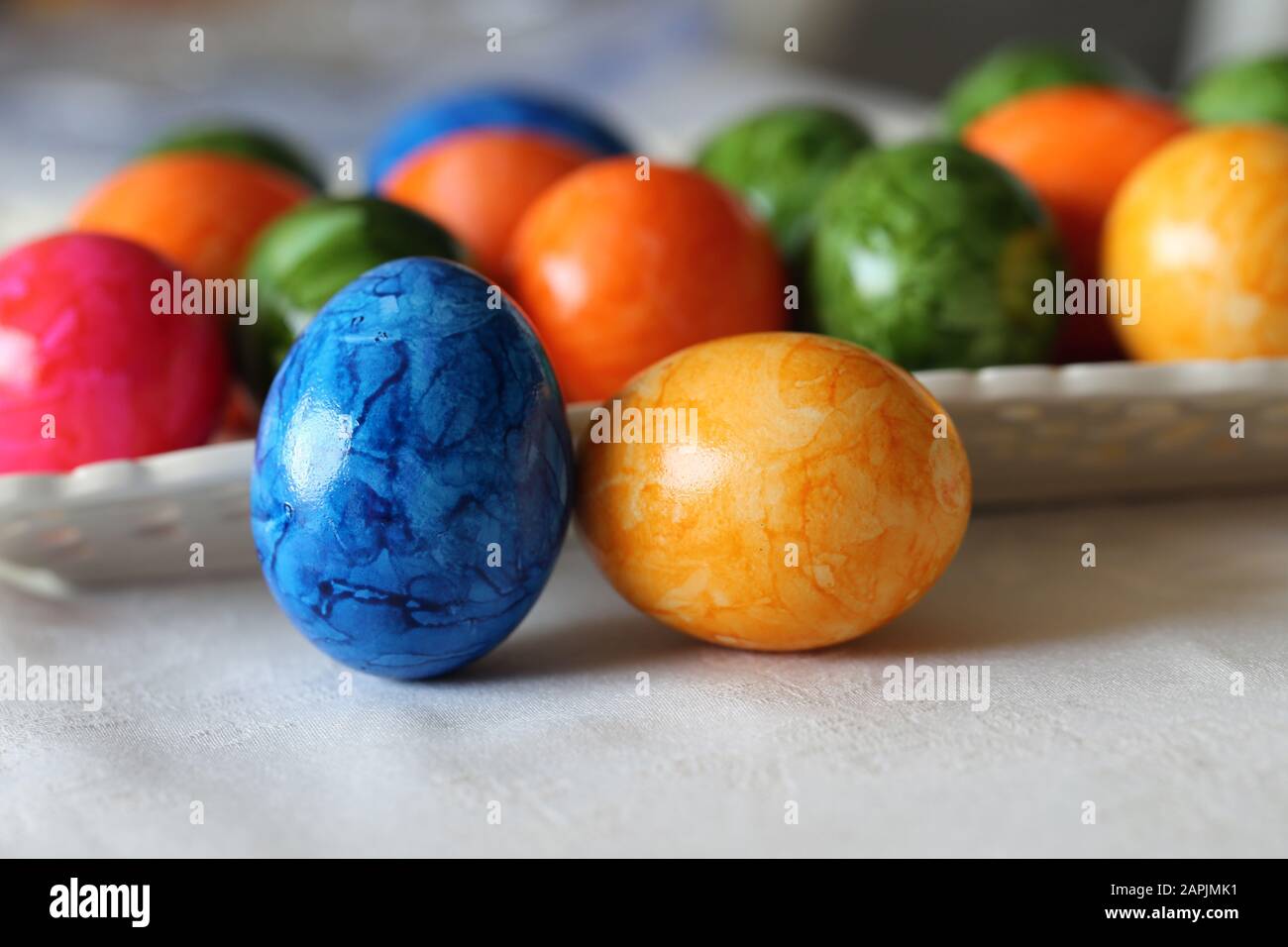 Decorazioni pasquali colorate e gioiose su un tavolo. Immagine a colori di closeup di molteplici uova di Pasqua dipinte con colori felici e vivaci. Foto Stock
