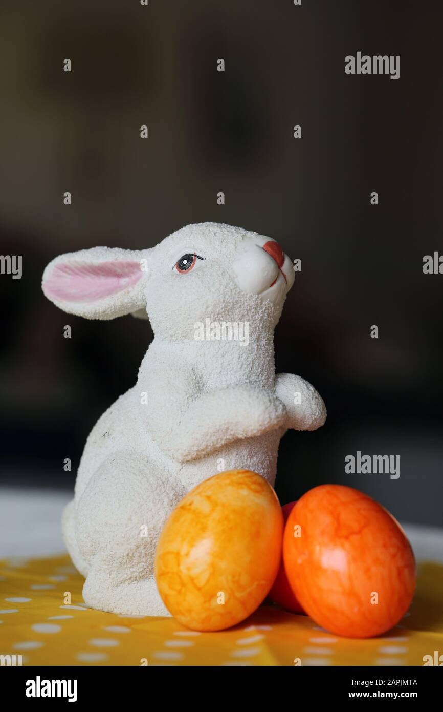 Decorazioni pasquali colorate e gioiose su un tavolo. Immagine a colori closeup di una figura bianca di coniglietto di Pasqua in ceramica e colorate uova di Pasqua dipinte. Foto Stock