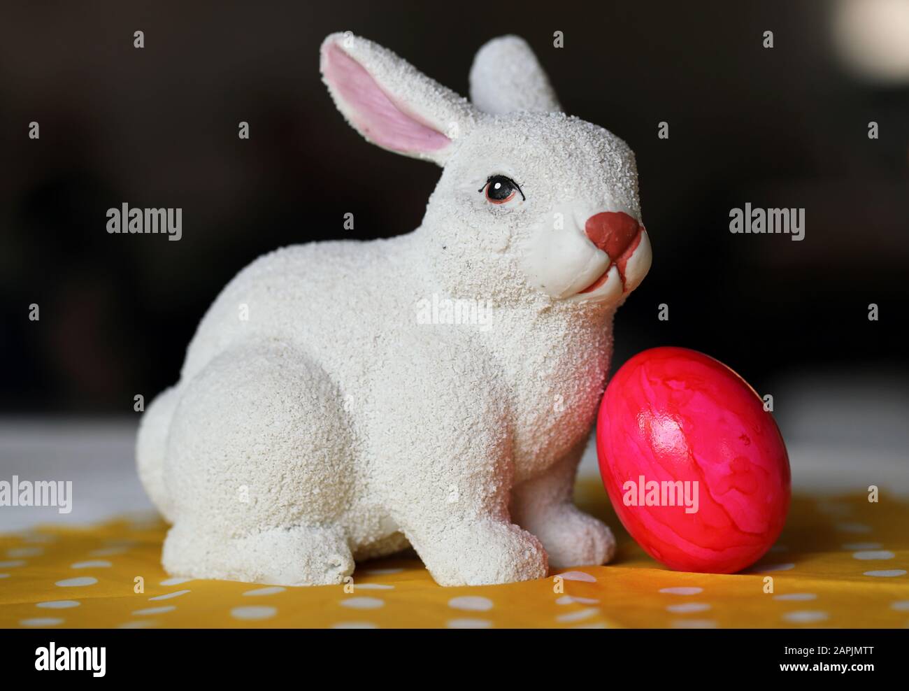 Decorazioni pasquali colorate e gioiose su un tavolo. Immagine a colori closeup di una figura bianca di coniglietto di Pasqua in ceramica e colorate uova di Pasqua dipinte. Foto Stock