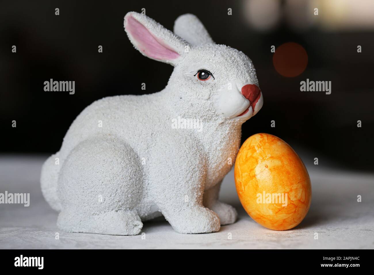 Decorazioni pasquali colorate e gioiose su un tavolo. Immagine a colori closeup di una figura bianca di coniglietto di Pasqua in ceramica e colorate uova di Pasqua dipinte. Foto Stock