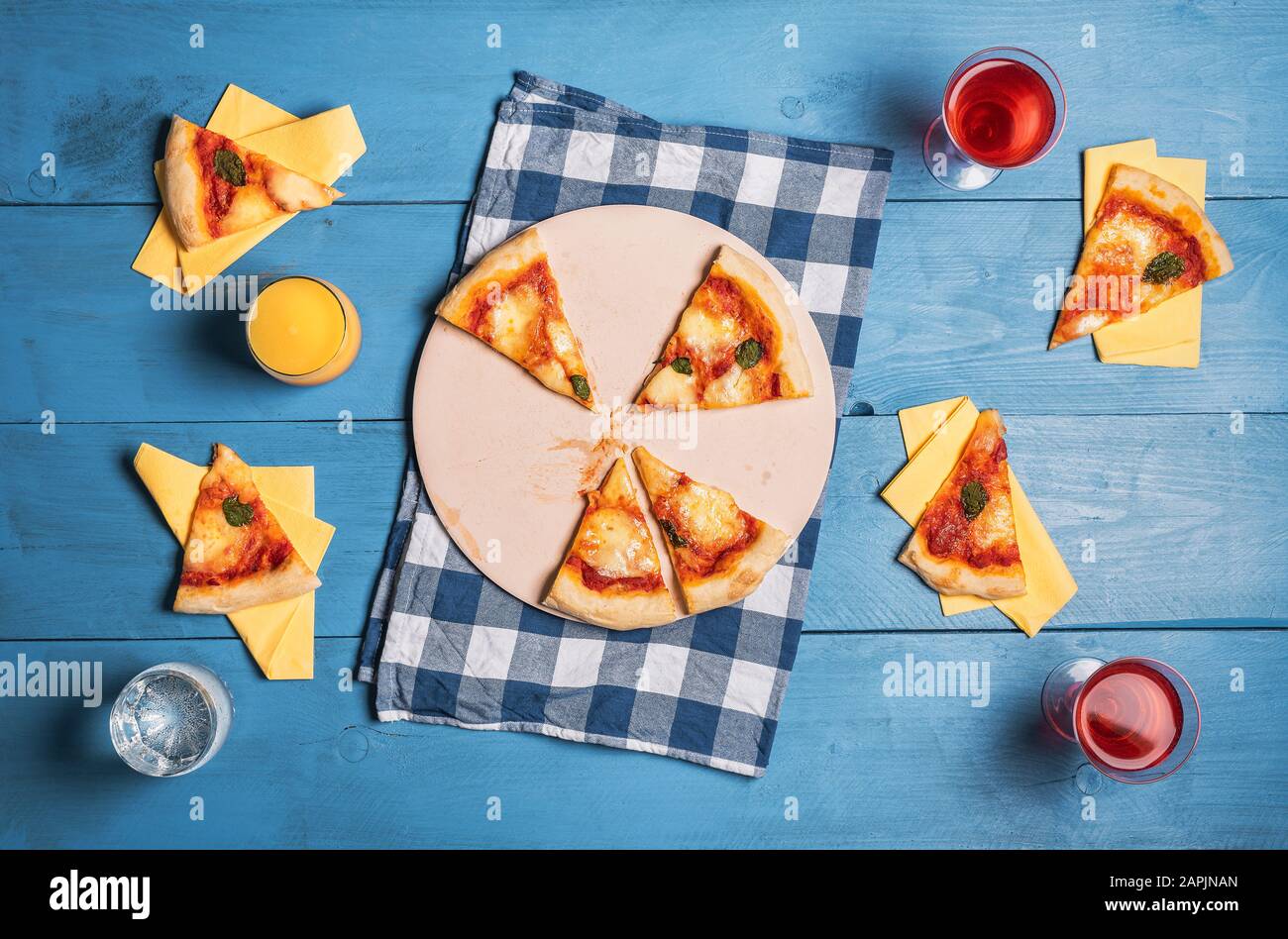 Tavolo da pranzo per quattro con pizza margherita, fette e bevande su un tavolo di legno blu. Oktoberfest cibo. Vista sul concetto di pizza da mangiare. Foto Stock