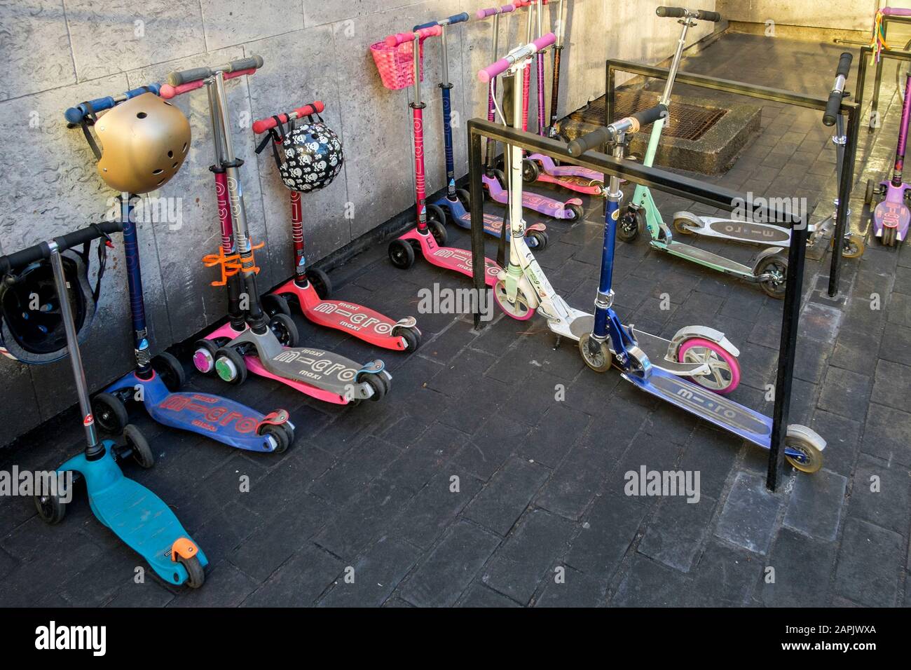 Scooter per bambini allineati in scuola urbana. Foto Stock