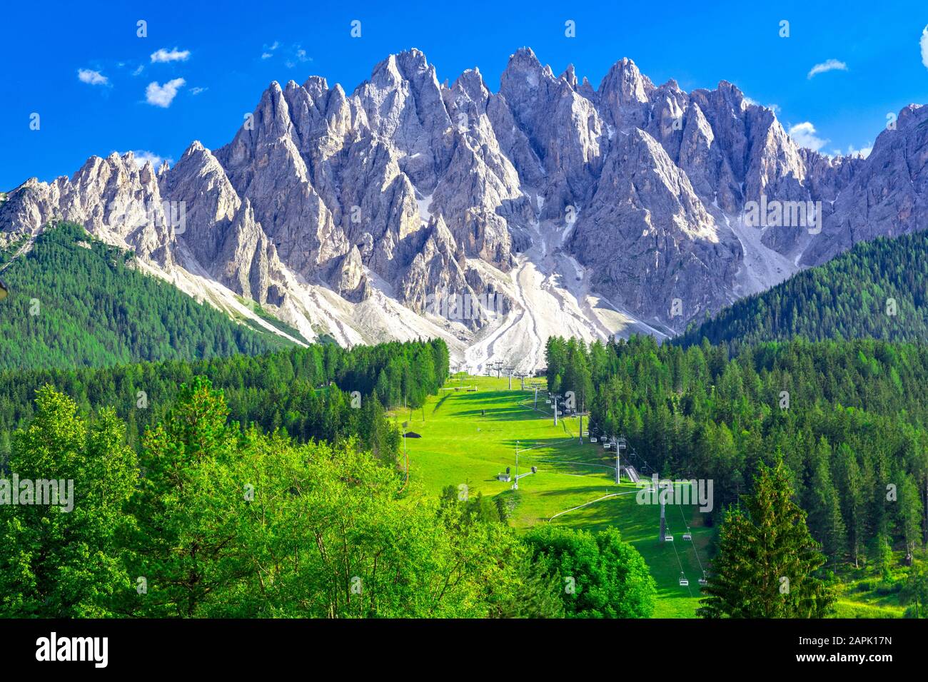 Paesaggio estivo nelle Dolomiti, pista da sci con funivia a San Candido con catena montuosa sullo sfondo Foto Stock