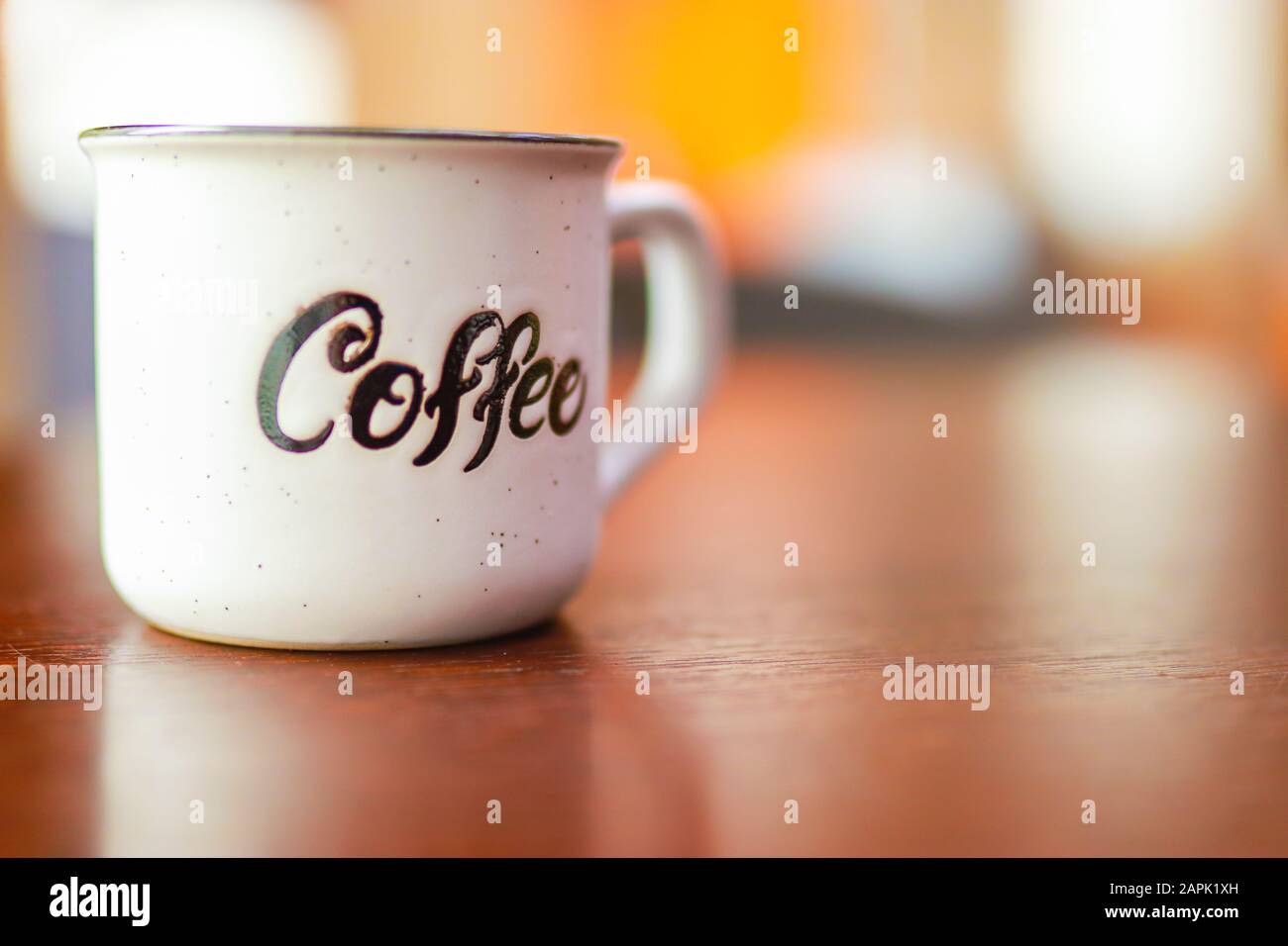 Tazza in metallo bianco smaltato con scritta caffè su tavolo in legno su sfondo sfocato. Luogo per il testo o la pubblicità Foto Stock