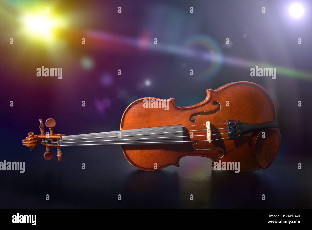 Violino su tavola di legno nero sul palco con luci colorate. Vista frontale. Composizione orizzontale. Foto Stock