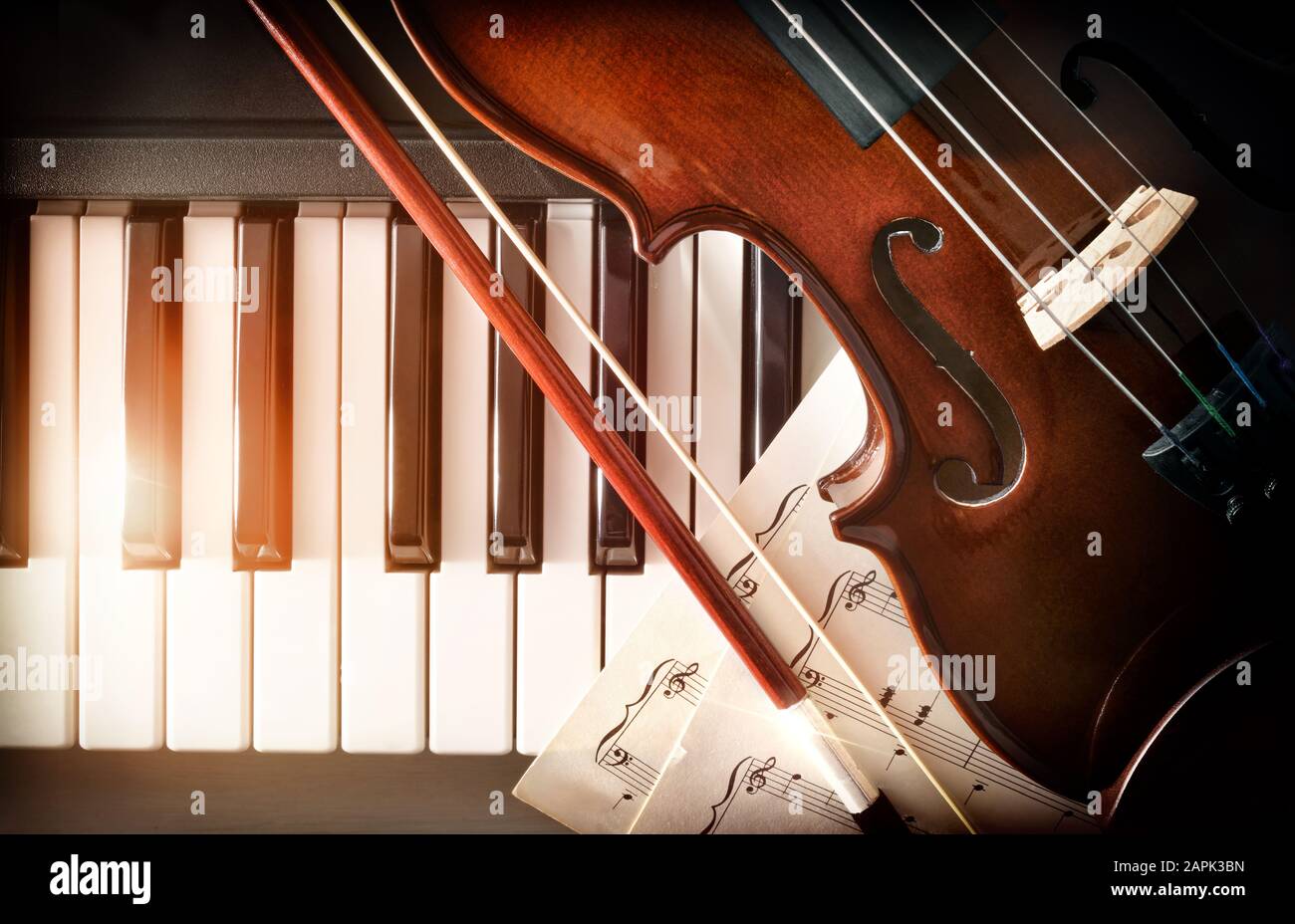 Arco violino e musica a fogli sui tasti piano. Concetto di interpretazione della musica da pianoforte e degli strumenti a corda. Vista dall'alto. Composizione orizzontale. Foto Stock