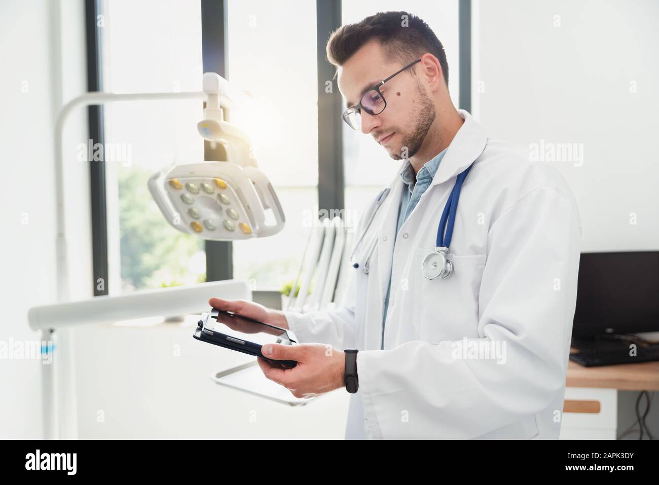 Medico utilizzando computer tablet nel suo ufficio. Moderna clinica medica Foto Stock