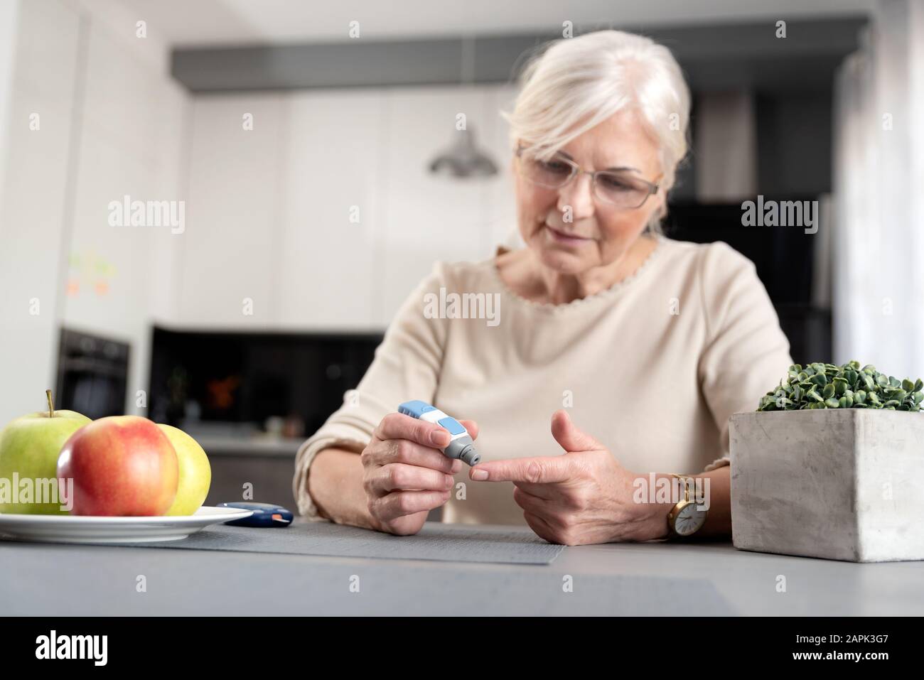 Donna senior di controllare il suo livello di glucosio nel sangue. Assistenza sanitaria il concetto di diabete Foto Stock