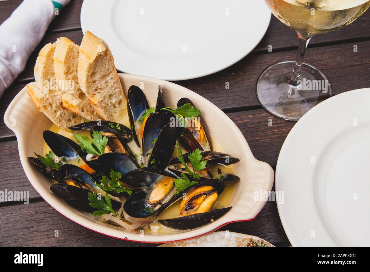 Cozze cotte su un tavolo con vino e antipasti di pollo spiedato Foto Stock