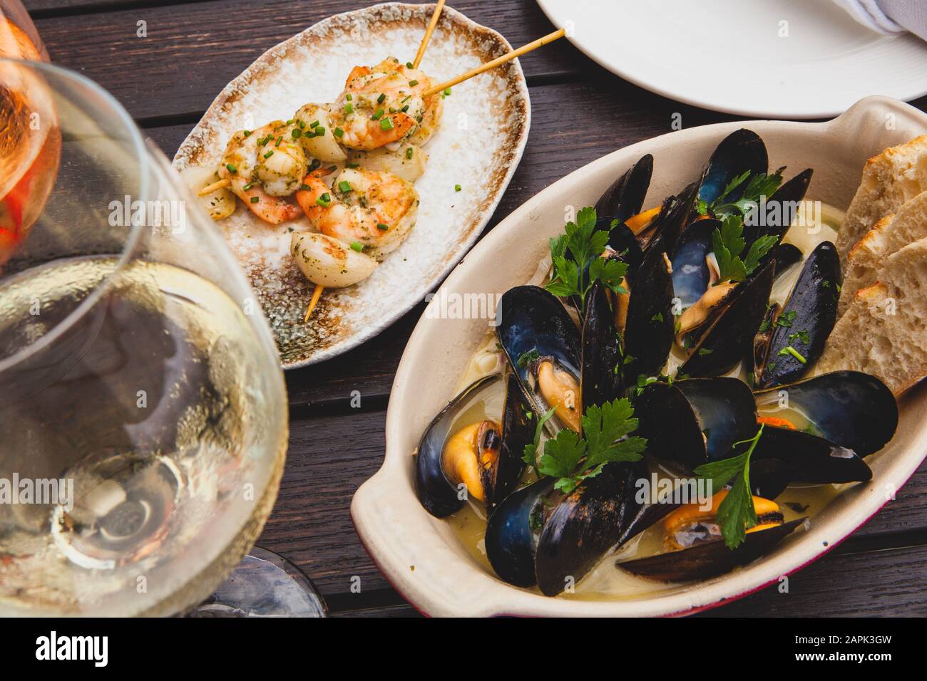 Cozze cotte su un tavolo con vino e antipasti di pollo spiedato Foto Stock