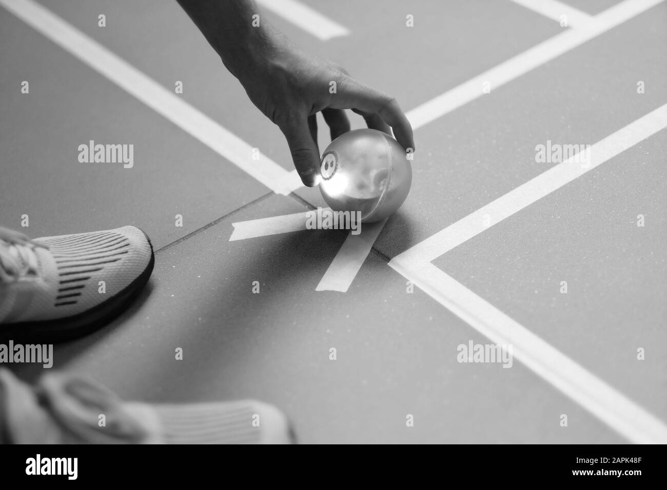 Mano dell'uomo con una palla luminosa da giocare sul campo segnato Foto Stock