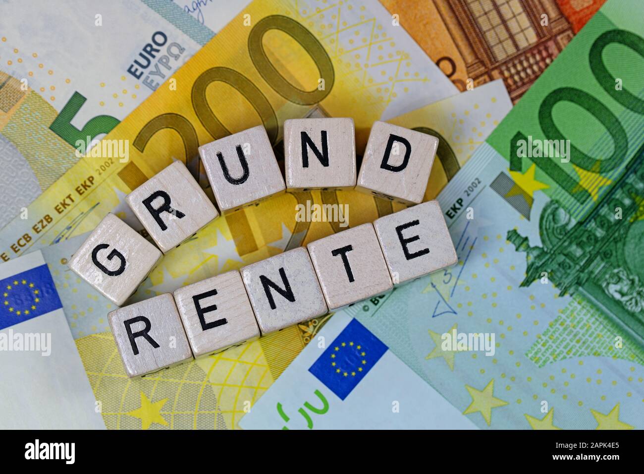 Cubi con lettere con parola tedesca Grundrente, affitto A Terra, su banconote Foto Stock