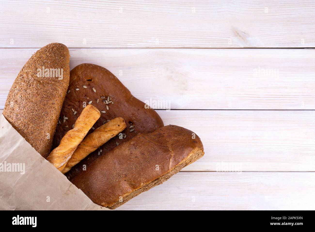 Pane in un sacchetto di carta su uno sfondo di legno chiaro, vista dall'alto Foto Stock