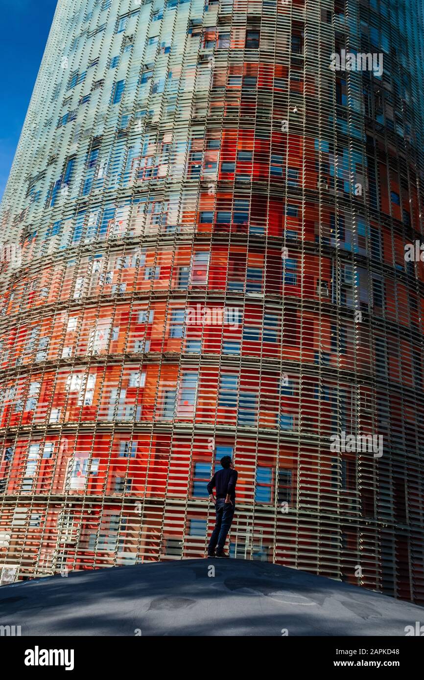 Vista posteriore di un uomo in piedi da solo con le mani in tasche e guardando in alto con la mente premurosa. La Torre di Glòries sullo sfondo (Barcellona, Spagna), Foto Stock