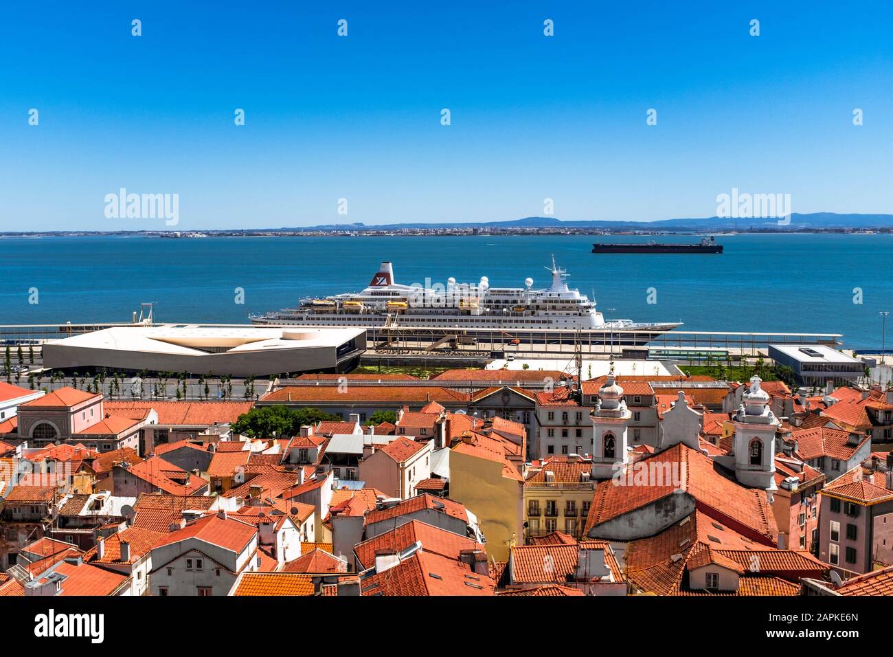Nave da crociera attraccata sulla costa di Lisbona con tetti di Alfama in primo piano e nave cisterna sullo sfondo. Foto Stock