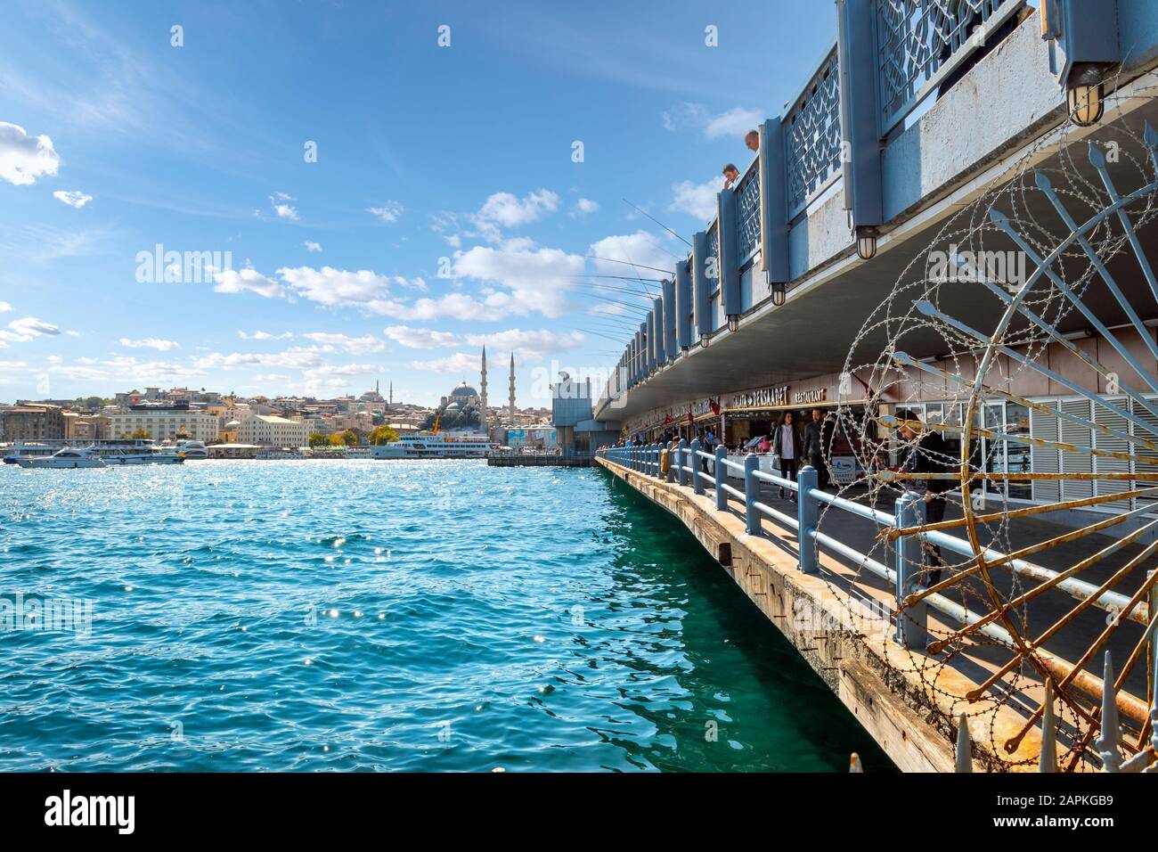 I due livelli del Ponte Galata sul fiume Bosforo in Istanbul Turchia, con caffè, turisti, pescatori con pali e moschee in vista Foto Stock