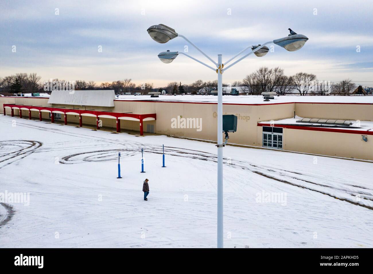 St Clair Shores, Michigan - UN uomo cammina attraverso un parcheggio vuoto presso un KMart chiuso nella periferia di Detroit, uno dei molti grandi magazzini che hanno chiuso Foto Stock