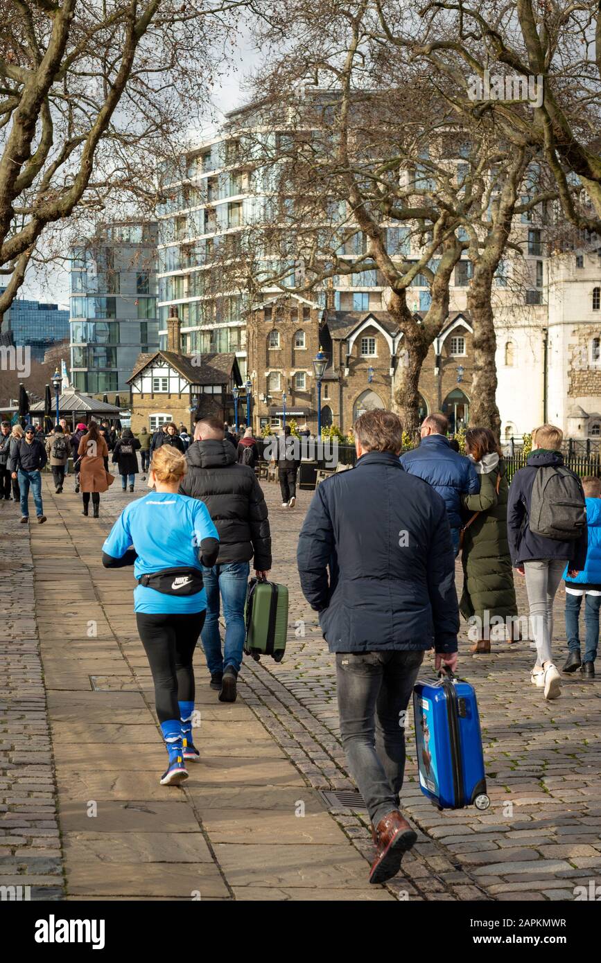 Jogger femminile che corre tra i turisti e le persone che camminano alla passeggiata della Torre di Londra, Londra, Regno Unito Foto Stock