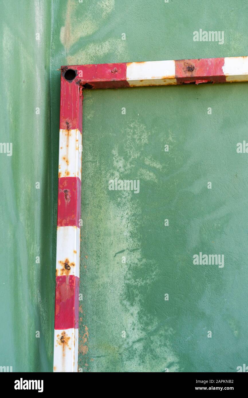 Arrugginito calcio obiettivo appoggiato su parete verde, vista parziale Foto Stock