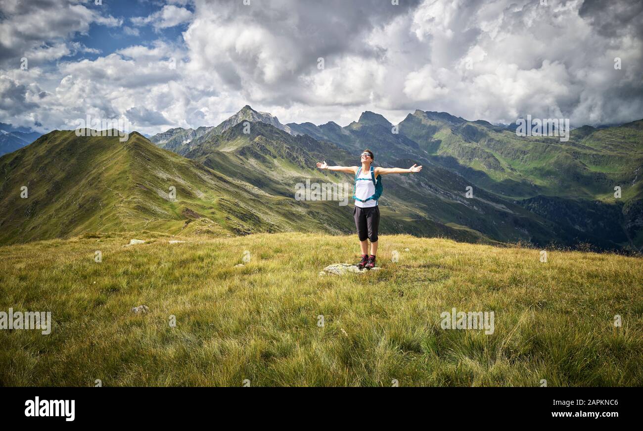 Donna allegra che fa una pausa dal trekking sul prato alpino, Val Passiria, Alto Adige, Italia Foto Stock