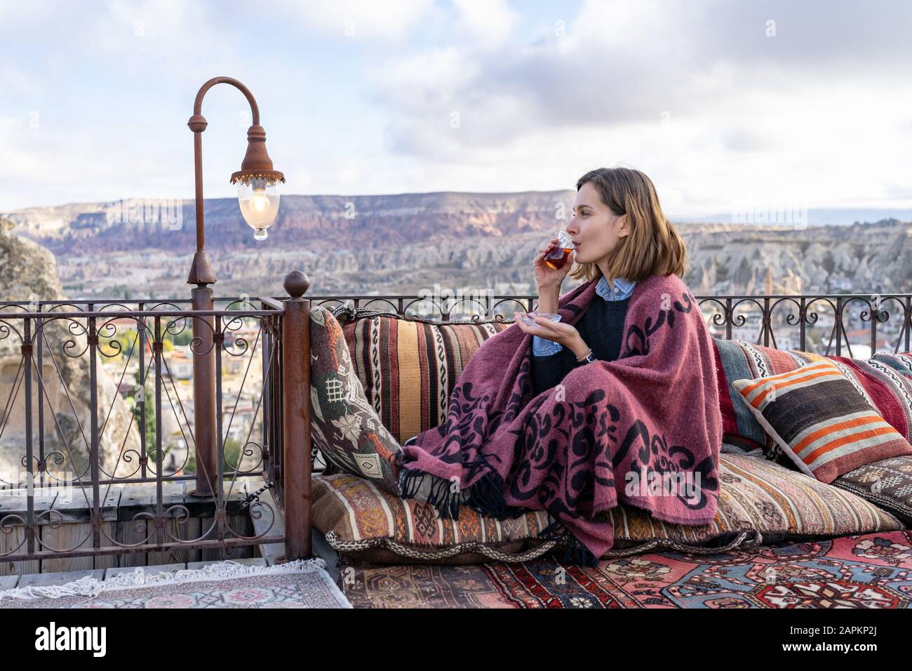 Donna sta bevendo il tè su un balcone in Cappadocia, Turchia Foto Stock