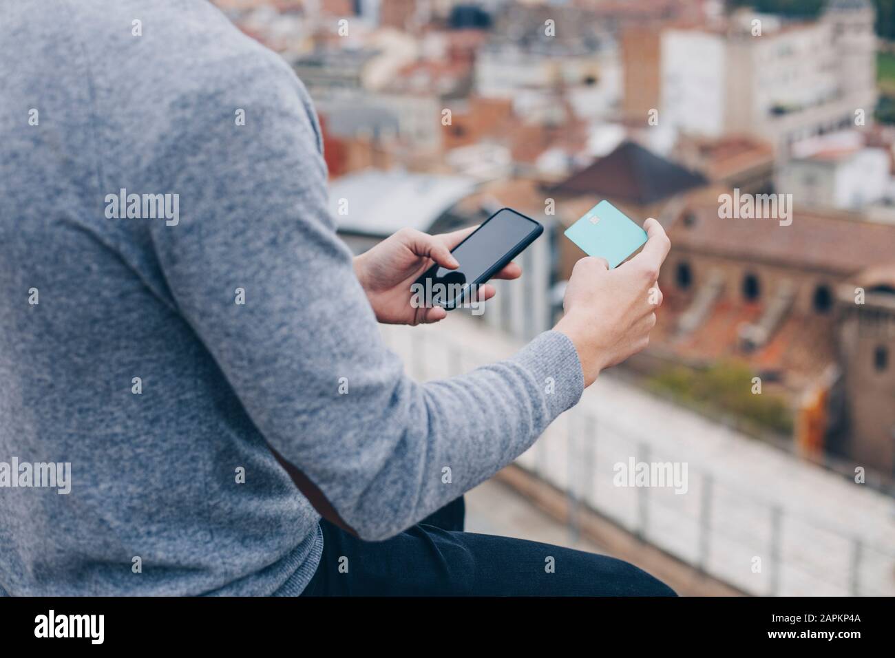 Primo piano di un giovane che paga con la carta di credito sul suo cellulare a Lleida Foto Stock