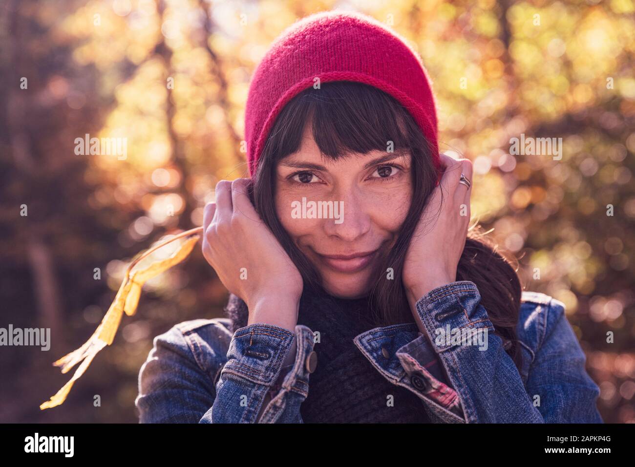 Donna che indossa cappello rosso e giacca in denim Foto Stock