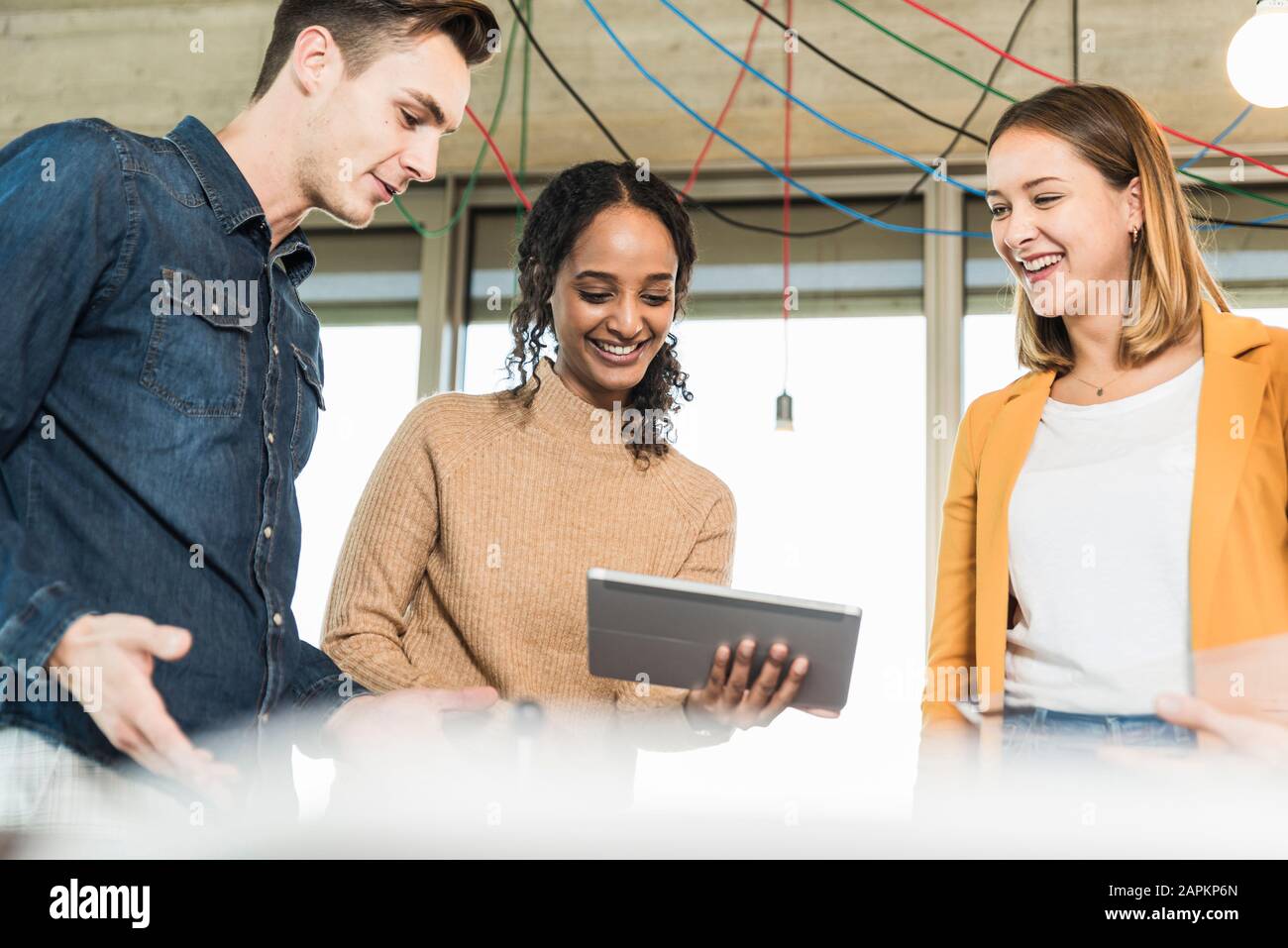 Giovani aziende che hanno una riunione in ufficio che condivide un tablet Foto Stock