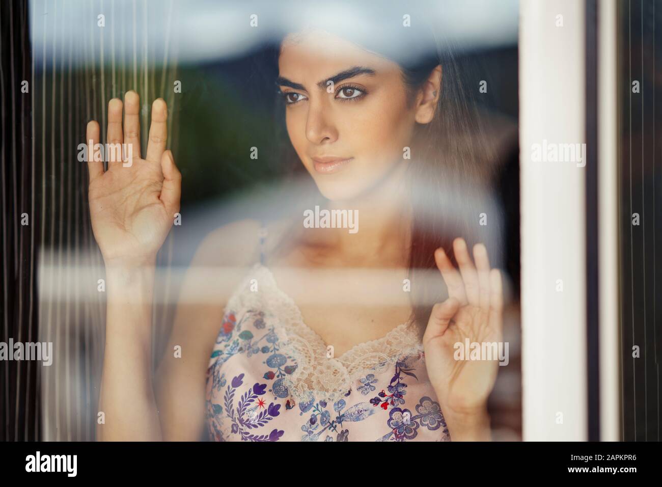 Ritratto di giovane donna guardando fuori della finestra Foto Stock