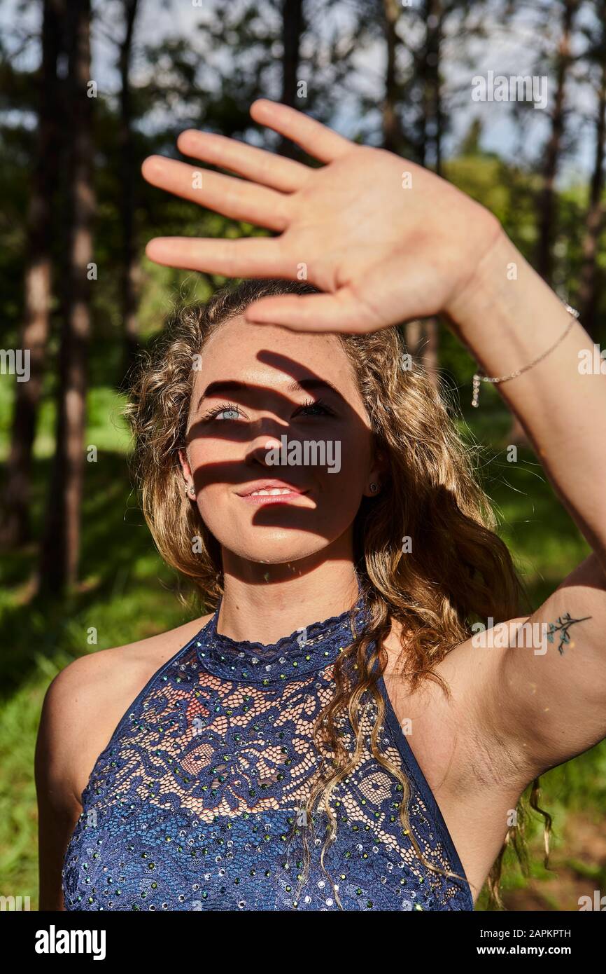 Giovane donna sorridente schermando gli occhi con la mano Foto Stock