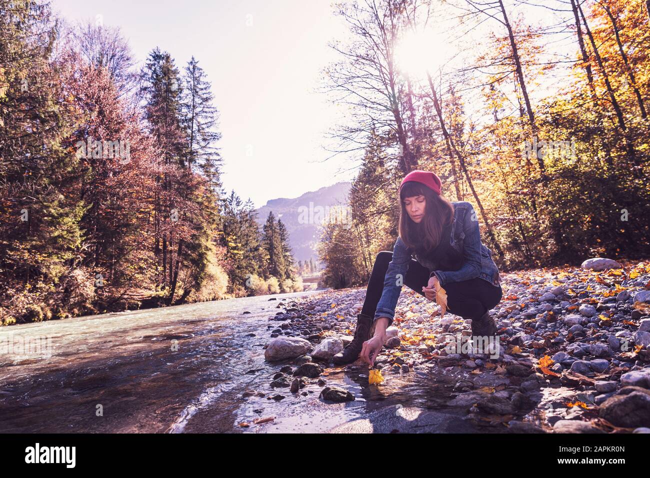 Donna che indossa un cappello di lana rossa e una giacca in denim sul lungofiume Foto Stock