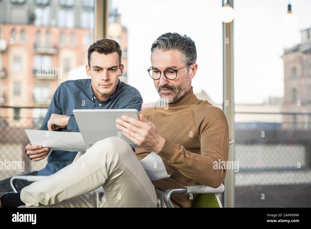 Uomo d'affari maturo con tablet e giovane che lavora in ufficio Foto Stock