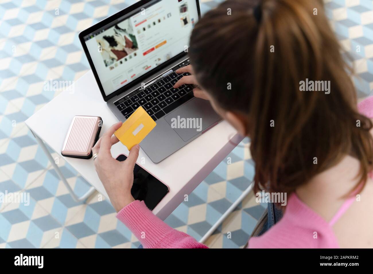 Vista posteriore della giovane donna che usa il laptop e la carta di credito Foto Stock