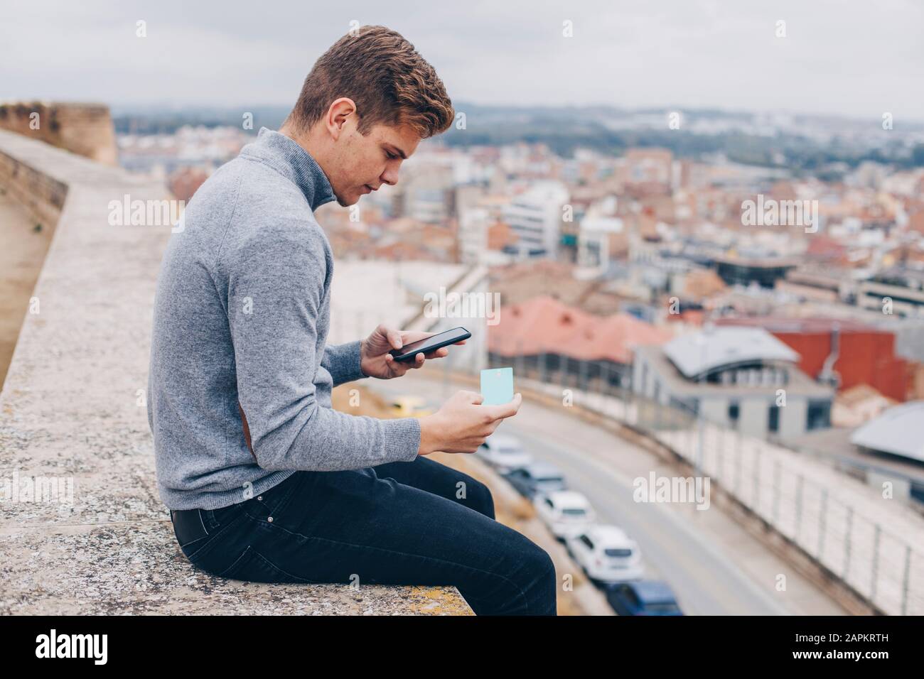 Giovane che paga con la carta di credito sul suo cellulare a Lleida Foto Stock
