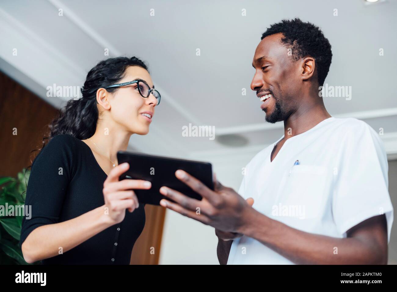 Dentista con compressa che parla con paziente femminile in chirurgia dentale Foto Stock