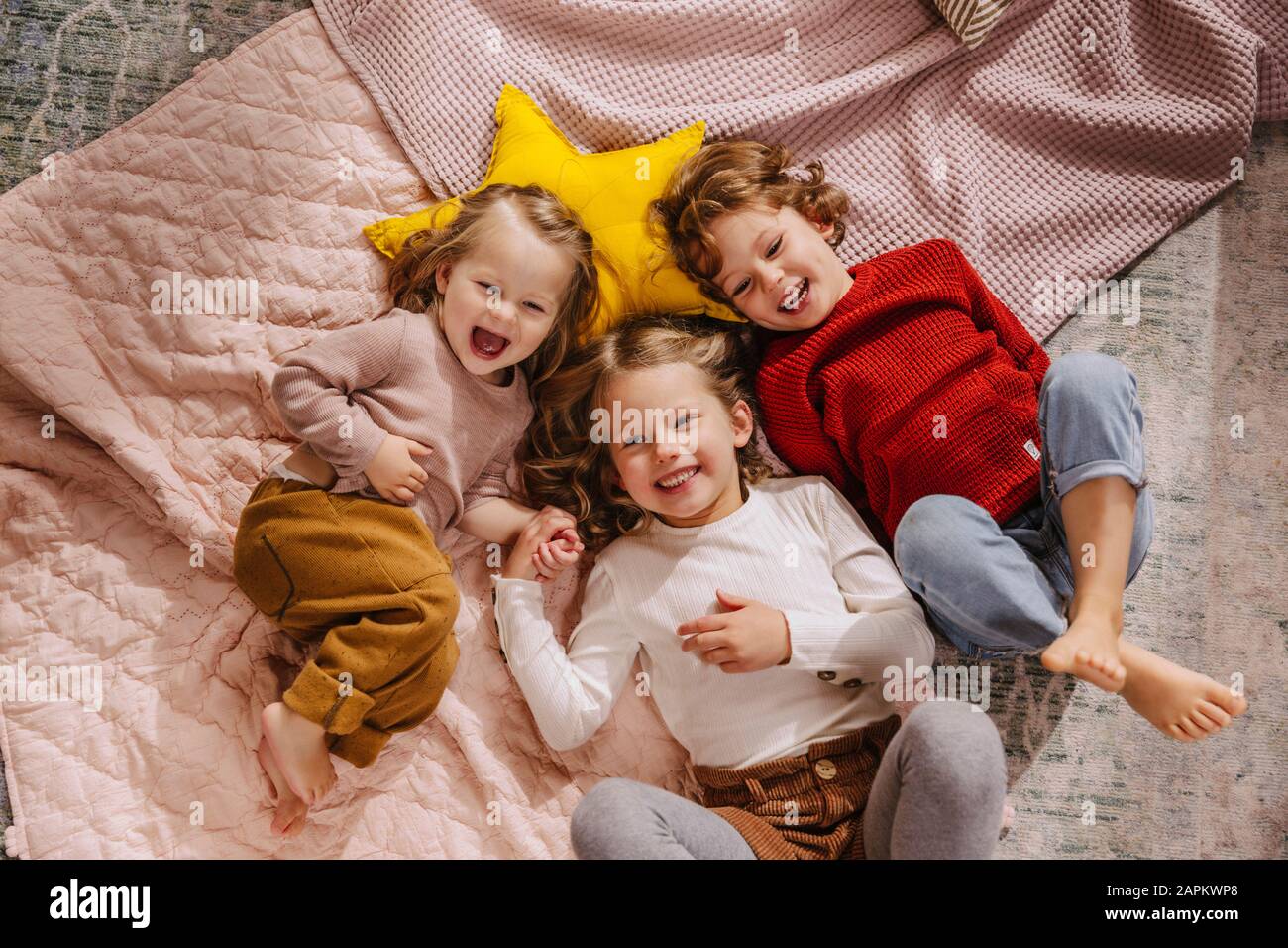 Tre ragazze felici sdraiate sulle coperte a casa Foto Stock