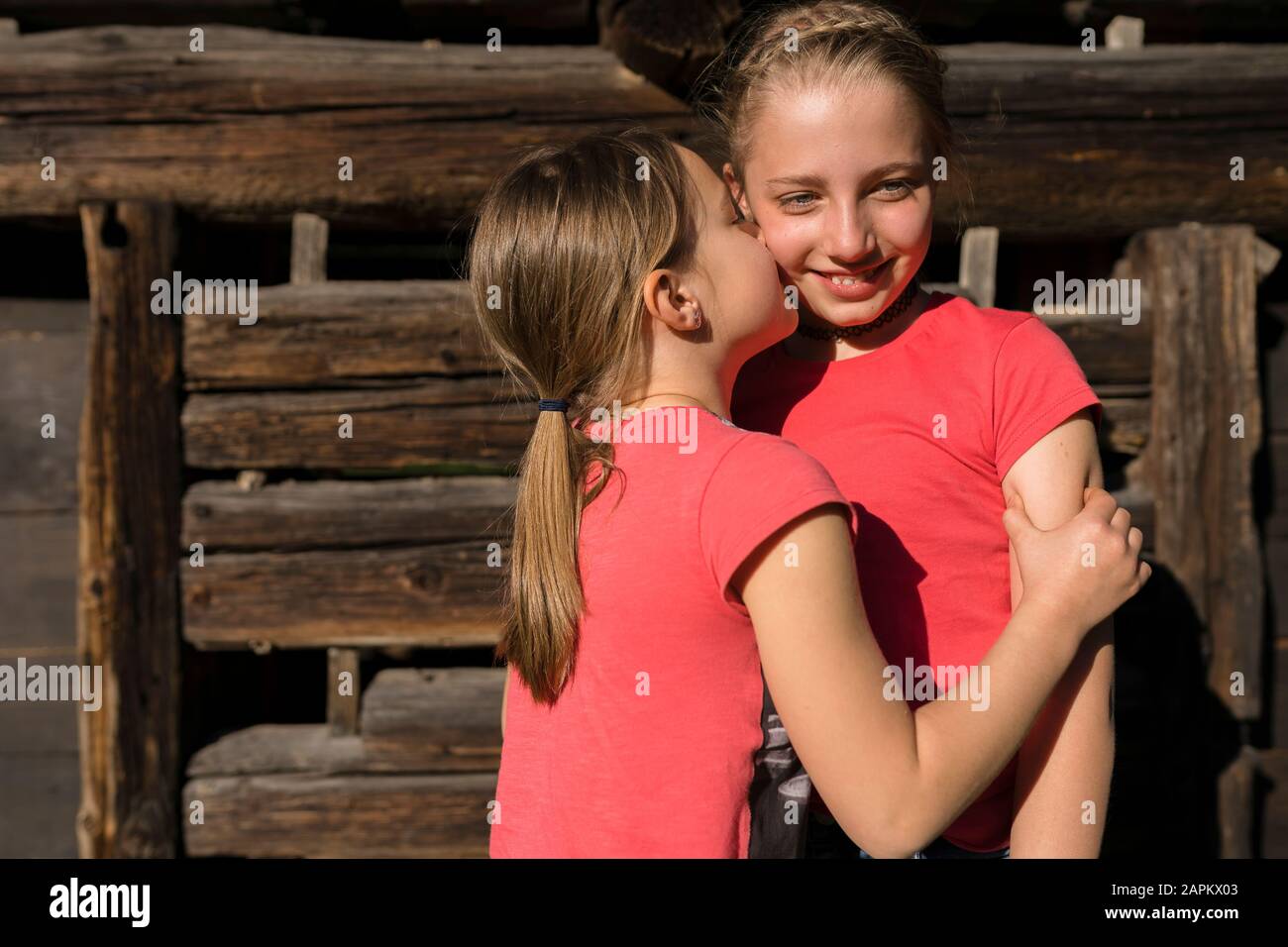 Ragazza che abbraccia e bacia sua sorella Foto Stock