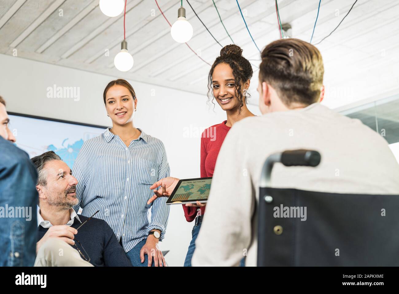 Giovane donna d'affari che condivide il tablet con i colleghi in ufficio Foto Stock