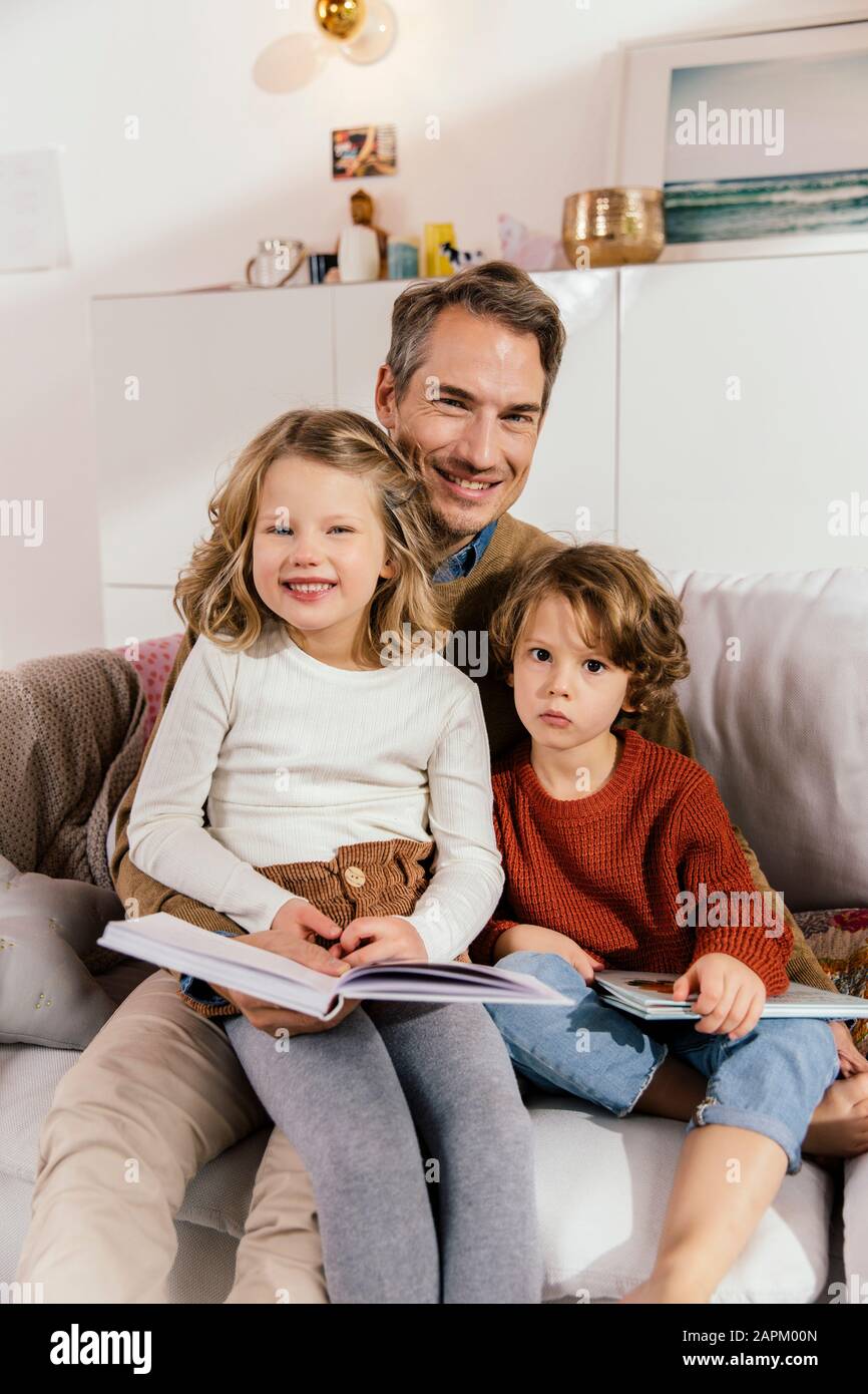 Ritratto di buon padre leggere libro con le figlie sul divano Foto Stock